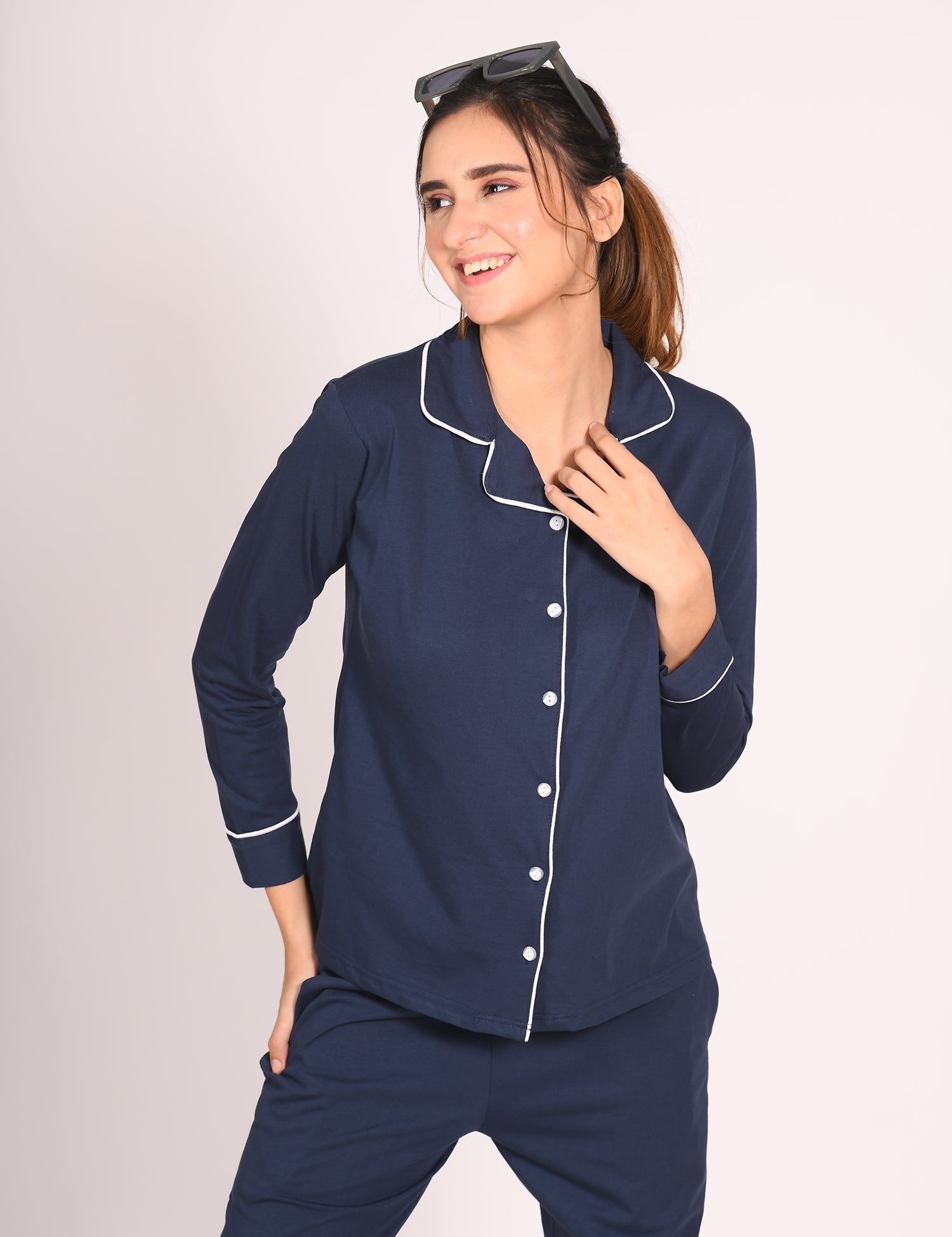 Woman in a solid navy 100% cotton full sleeve nightsuit by NapStory, smiling with a relaxed pose.