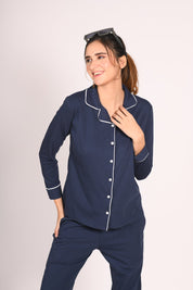 Woman in a solid navy 100% cotton full sleeve nightsuit by NapStory, smiling with a relaxed pose.