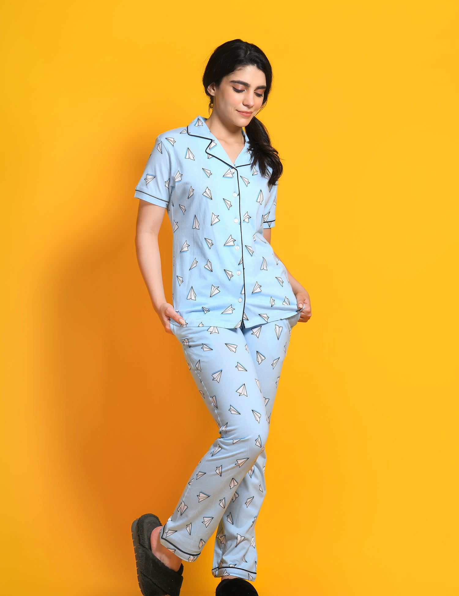 oung girl in a Paper Plane Printed Pyjama Set nightwear by NapStory, standing in style.